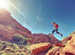 Leaping into the Summer - making use of the Aries Moon and Mars in Virgo. A Man leaping over Red Rocks.